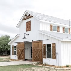 a white barn with wooden doors and windows