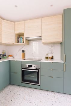 a kitchen with green cabinets and white counter tops, including an oven in the middle