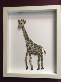 a giraffe made out of rocks in a white frame