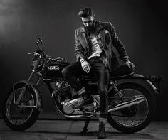 black and white photograph of a man sitting on a motorcycle with his hand on the seat