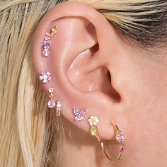 a close up of a woman's ear with different colored stones on the side