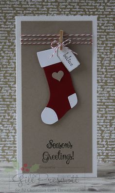 a christmas card with a stocking hanging from a line on a string that says season's greeting