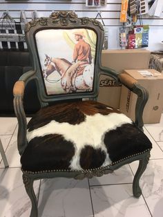 a cow hide chair with a cowboy painting on it's back in a store