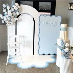 a white and blue wedding cake sitting on top of a table next to a chair