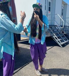 two women standing next to each other in front of a truck with their hands together