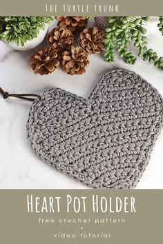 the heart pot holder is crocheted and sits next to some pineconi