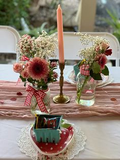 two vases filled with flowers sitting on top of a table next to a candle