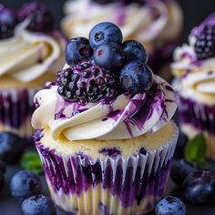 blueberry cupcakes with white frosting and fresh berries on top are displayed