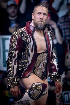 a man with a beard wearing a wrestling suit and holding his hands in his pockets