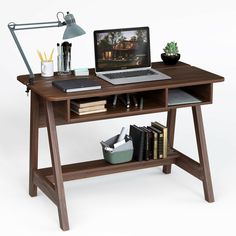 a laptop computer sitting on top of a wooden desk next to a lamp and books