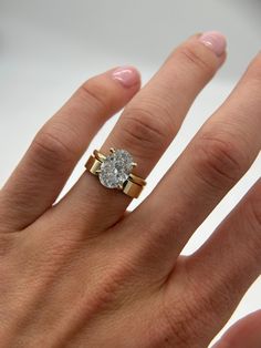 a woman's hand with a diamond ring on top of her finger and the other hand holding it