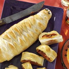 a blue plate topped with pastries on top of a red table cloth next to a knife