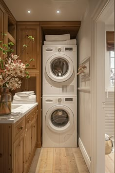 a washer and dryer in a small room with wooden cabinets on either side