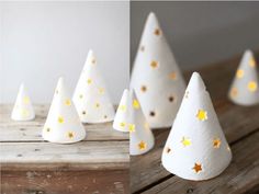 small white paper christmas trees with gold stars on them, sitting on a wooden table