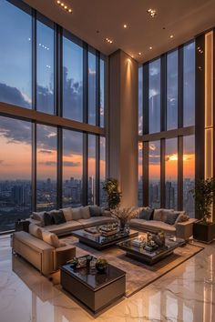 a living room filled with lots of furniture and large windows overlooking the city at sunset