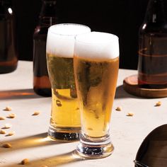 two glasses of beer sitting on top of a table