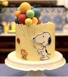 there is a cake decorated with balloons and a dog on the top one has a balloon attached to it