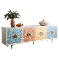 a multicolored sideboard with three drawers and a potted plant on top