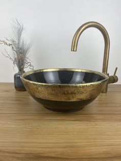 a black and gold bowl sink sitting on top of a wooden counter next to a faucet