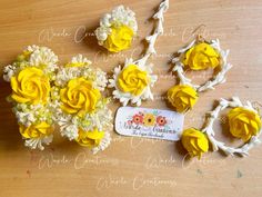 yellow and white flowers are arranged on a wooden table with a name tag next to them