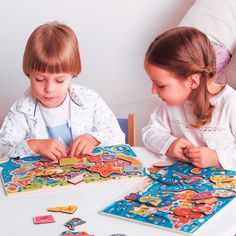 two young children playing with puzzles on a table