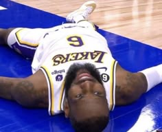 a basketball player laying on the floor with his head in his hands and eyes closed