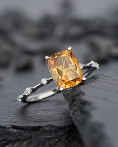 a yellow diamond ring sitting on top of a rock