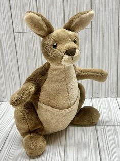 a brown stuffed animal sitting on top of a wooden floor