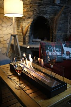 two glasses of wine on a table in front of a fireplace