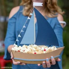 a woman holding a paper boat with popcorn in it