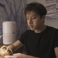 a person sitting at a table with a sandwich in front of him and an air humider on the wall behind them