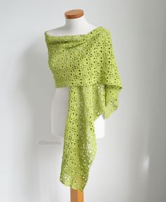 a green crocheted shawl draped over a mannequin