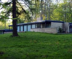 a house in the middle of a field with trees around it and grass on the ground