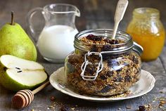 granola in a glass jar next to pears and honey