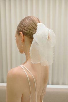 a woman with a flower in her hair wearing a white dress and gold earring