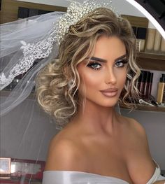 a woman with blonde hair wearing a veil and wedding dress in front of a mirror