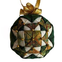 an ornament made out of fabric with gold beads and bows on it's side