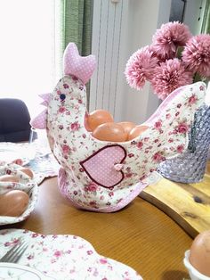 an egg holder with eggs in it sitting on a table next to other plates and flowers