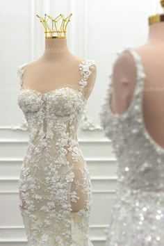 the back of a wedding dress with a crown on it's head in front of two mannequins