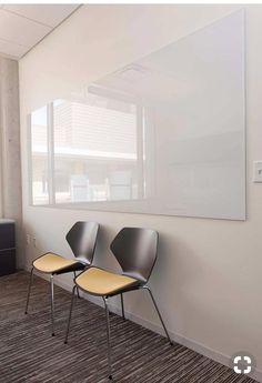 two black chairs are sitting in front of a white board on the wall next to a window