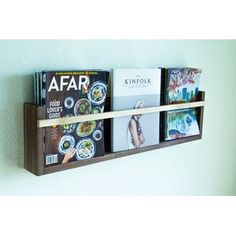 a wooden shelf with books and magazines on it in front of a wall mounted book rack