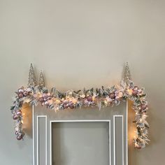 a decorated fireplace mantle with christmas lights and garland on it's sides in front of a mirror