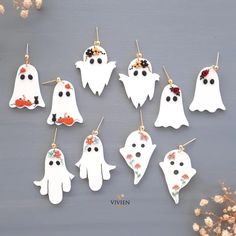 twelve white ghost earrings with black eyes and red noses, hanging from gold earwires