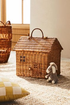 a wicker basket with a house on it and a stuffed animal sitting in front of it