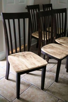 three wooden chairs sitting next to each other on a tile floor in front of a door