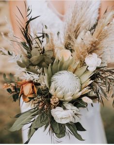 a bride holding a bouquet of flowers and feathers