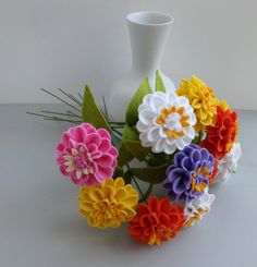 a white vase filled with colorful flowers on top of a table