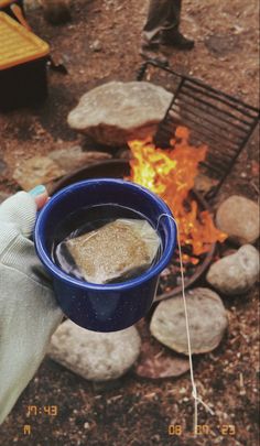 a person holding a blue cup over a fire