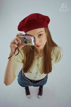 a young woman is taking a selfie with her cell phone while wearing a red beret