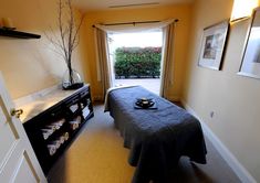 a room with a bed, dresser and table in it that has a black blanket on it